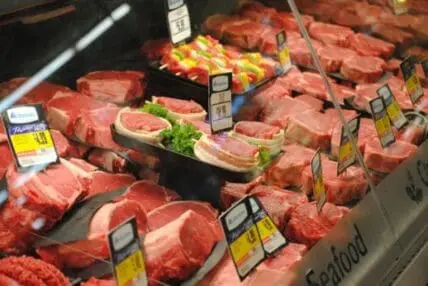 Raw meat cuts displayed in a butcher case with price labels