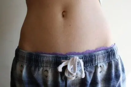 Person's midsection showing abdominal area and waistband of gray pants with white drawstring