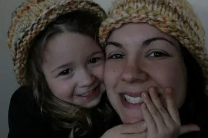 Woman and child wearing knit beanies, smiling together