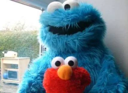 Cookie Monster and Elmo posing together outdoors