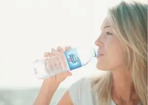 Woman drinking from a plastic water bottle outdoors