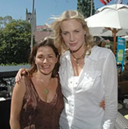 Two women posing together at an outdoor event under a white umbrella