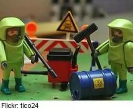 Toy figurines in hazmat suits handling a radioactive waste barrel