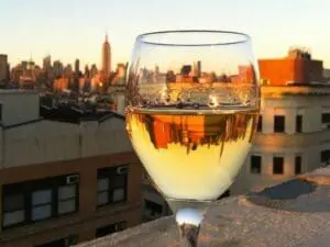 Glass of white wine with NYC skyline reflected in the glass at sunset