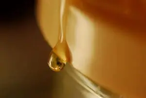 Golden honey dripping from a wooden dipper
