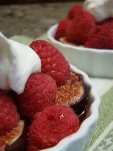Raspberries with whipped cream and caramelized topping in white bowls