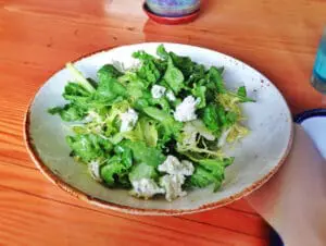 Fresh green salad with crumbled cheese on a white plate