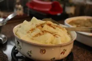 Creamy mashed potatoes with cinnamon garnish in a decorative bowl with spoon