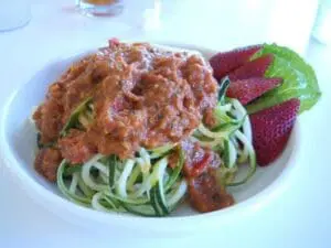 Spiralized zucchini noodles topped with tomato sauce and garnished with fresh strawberries