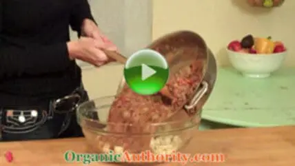 Person pouring ground meat into a large bowl for Spicy Grass-Fed Organic Bolognese preparation