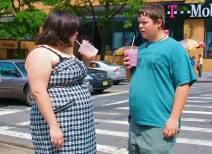 Two people drinking beverages on a city street
