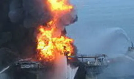 Offshore oil platform engulfed in flames with firefighting vessel spraying water