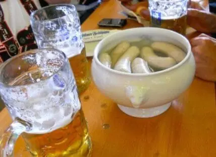 Mug of beer with glasses of water and a bowl of pickles on a wooden table