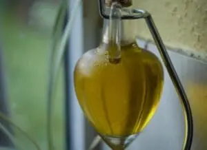 Golden extra-virgin olive oil dripping from a dispenser into a clear container