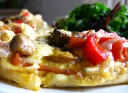 Vegetable omelet with peppers, mushrooms, and greens on a white plate