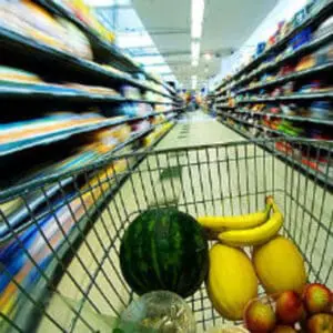 Shopping cart filled with fresh produce in supermarket aisle