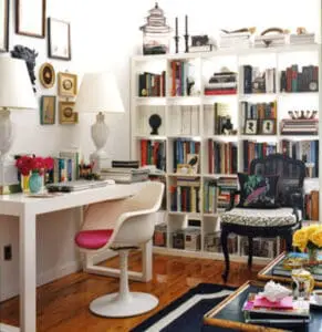 Organized home office with white shelving unit filled with books and decorative items, white desk