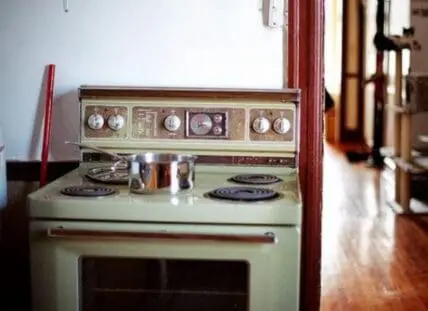Vintage avocado green electric stove with coil burners and clock display panel