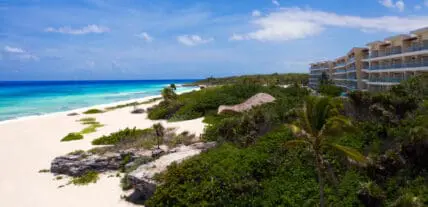 Beachfront resort with white sand, turquoise water, and tropical vegetation in Playa del Carmen