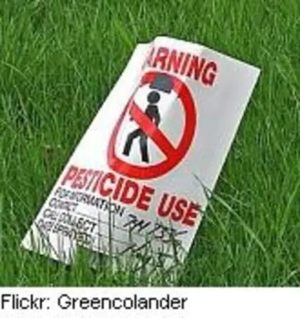 Warning sign for pesticide use posted on grass lawn