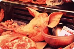Raw pig's head and meat cuts displayed at a butcher counter
