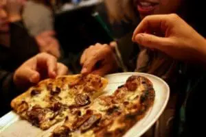 People sharing a slice of pizza at a social gathering