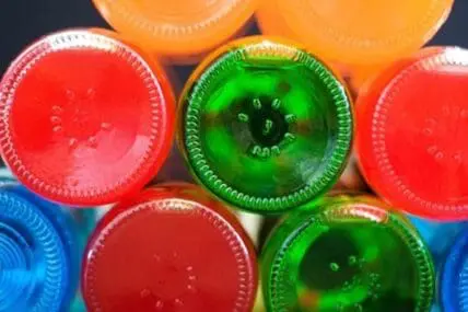 Colorful plastic cups filled with red, green, orange, and blue sugary drinks
