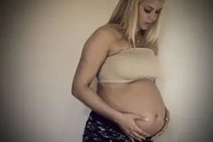 Pregnant woman cradling her belly while looking down