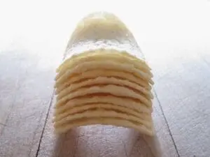 Stack of thin crepes or pancakes dusted with powdered sugar on a wooden surface