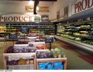 Produce section of a grocery store with refrigerated vegetables and fresh produce displays