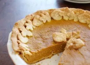 Pumpkin pie with decorative cashew garnish and one slice removed