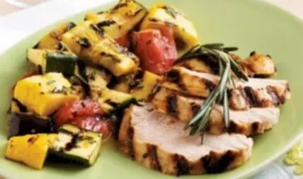 Grilled pork chops with charred vegetables on a green plate