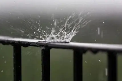 Rainwater splashing on a metal gutter during heavy rain