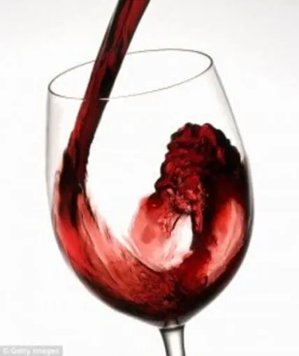 Image of red wine from Stag's Leap Wine Cellars being poured into a red wine glass with blurred out wine bottles and glasses in the background.