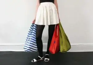 Woman holding three colorful reusable shopping bags