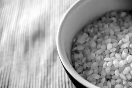 Bowl of uncooked white rice on a striped cloth surface