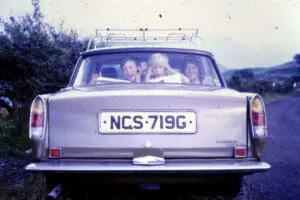 Family in a classic car on a road trip with luggage rack on roof