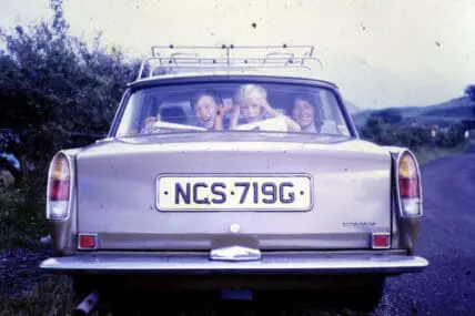 Family in a classic car on a road trip with luggage rack on roof
