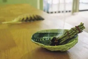 Dried sage bundle in a green abalone shell on wooden surface