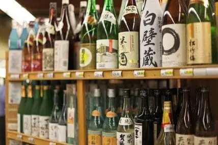 Shelves of Japanese sake bottles with labels displayed in a retail shop