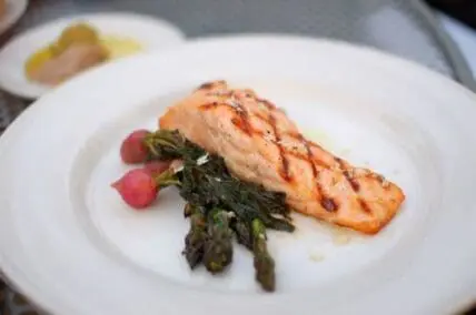 Grilled salmon fillet with asparagus and radishes on a white plate
