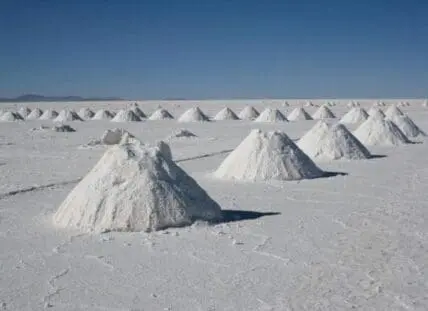 Salt evaporation ponds with conical salt piles in a desert landscape