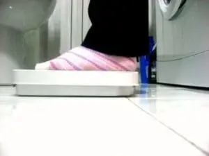 Person weighing themselves on a bathroom scale wearing pink striped clothing
