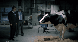 Two men in suits observe a cow in an industrial facility during a Chipotle advertisement