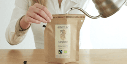Person pouring water into a disposable paper coffee pouch with Glowee's Honduras label