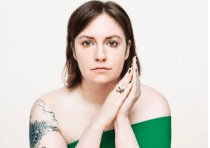 Woman with shoulder tattoo in green dress against white background
