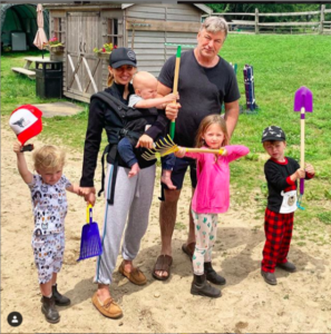 Hilaria Baldwin with family members holding gardening tools in a backyard