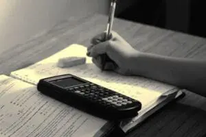 Student doing homework with calculator and study materials on desk