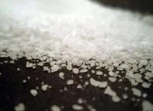 Close-up of white sea salt crystals on a dark surface