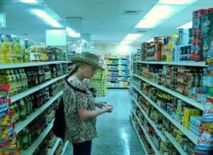 Person shopping in grocery store aisle with packaged food products on shelves